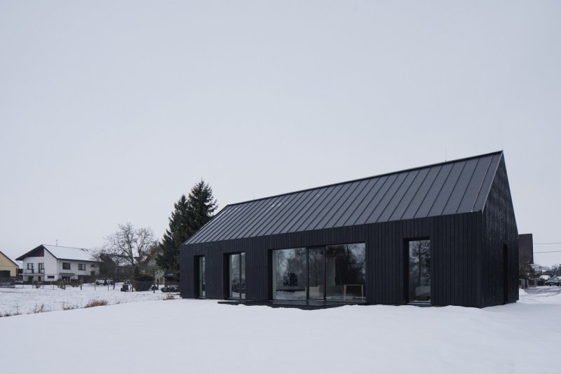 Dům je velkými prosklenými plochami propojený se zahradou. (Přízemní dům s fasádou z opalovaného dřeva; Luni architekti)