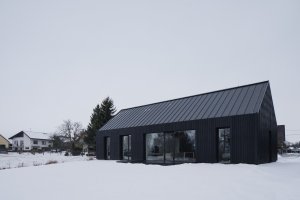 Dům je velkými prosklenými plochami propojený se zahradou. (Přízemní dům s fasádou z opalovaného dřeva; Luni architekti)