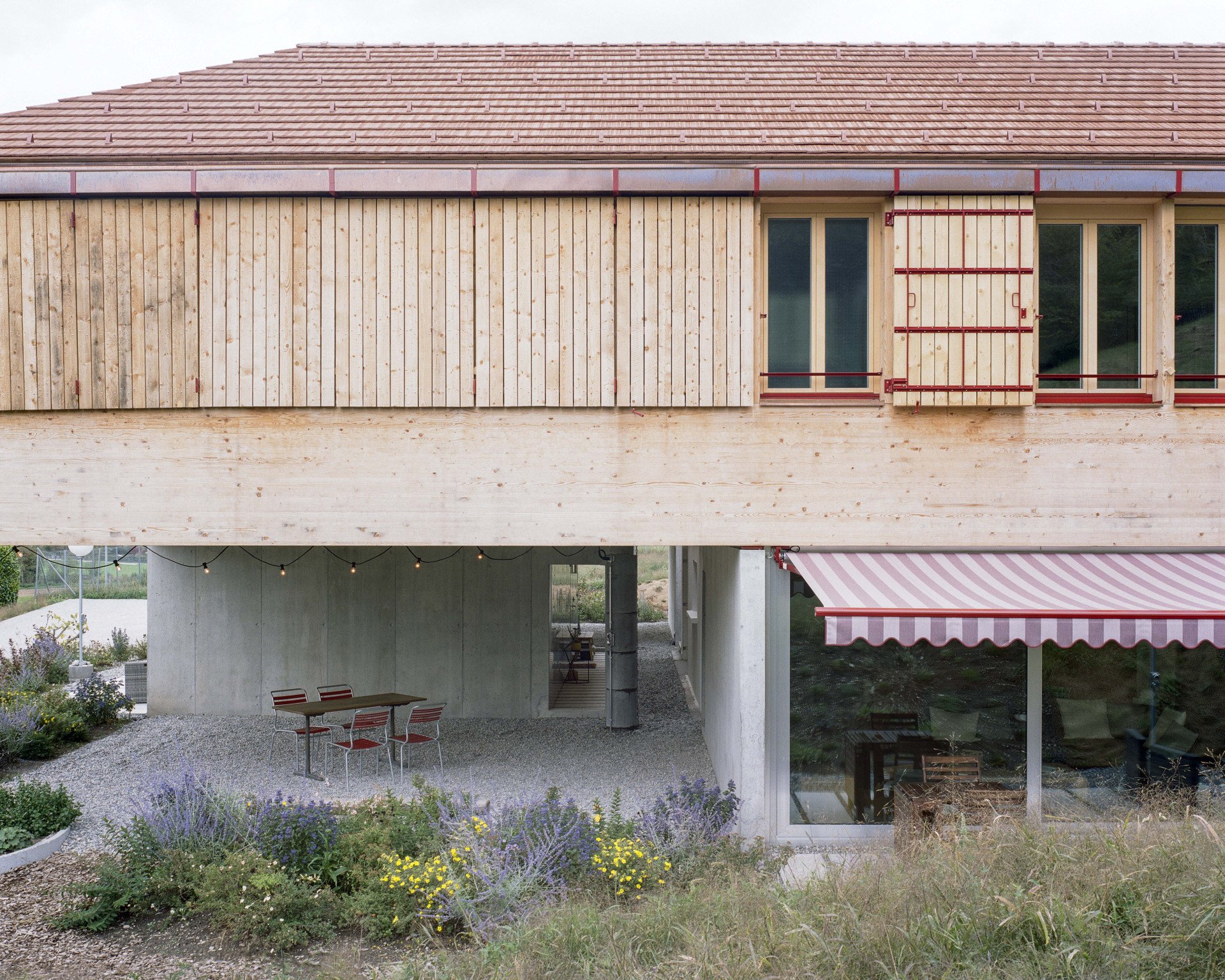 Rodinné komunitní bydlení ve Villy, Madeleine architectes, Studio François Nantermod: Fasáda si bere inspiraci z tvarosloví místní tradiční architektury, nepůsobí však jako pokus o jeho napodobení