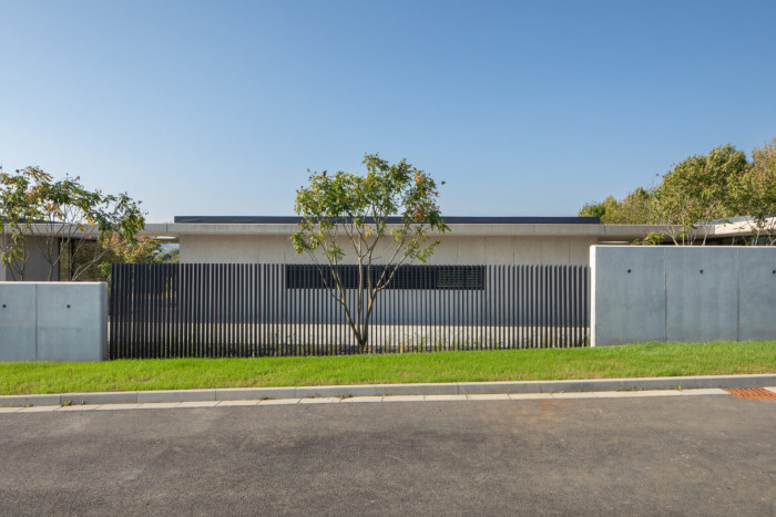 Oplocení směrem k ulici je řešeno kombinací betonu a lamel pro zachování soukromí. (Rodinný dům v Novém Jičíně – Žilině; Kamil Mrva Architects)