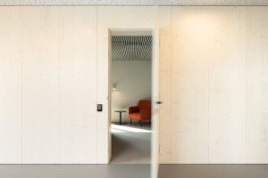 Interiér pracuje s akustickými panely, HPL deskami a březovou překližkou. (Bytový dům od KOMA MODULAR)
