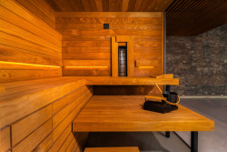 Designová finská sauna TAO v privátním spa disponuje tmavým obkladem, černými doplňky, stěnami zasklenými zatmaveným sklem a zádovým infrapanelem. 