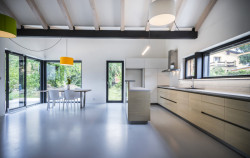 Rodinný dům v Písnici, daviddavidová architekti: Hlavní obytný prostor s kuchyní se otevírá do jejich krovů a taky ven do zahrady, jsou zde totiž francouzská okna