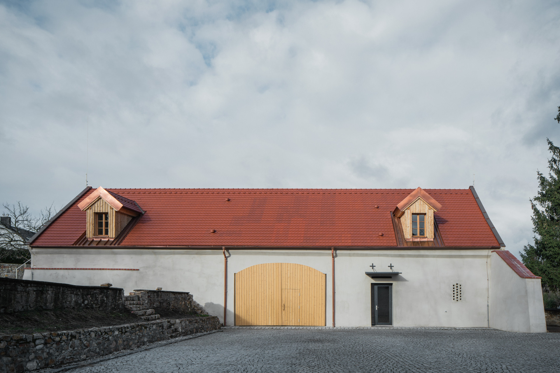 Bývalá farní stodola se zavřenými vraty. (Komunitní centrum v bývalé stodole, studio Raketoplán)