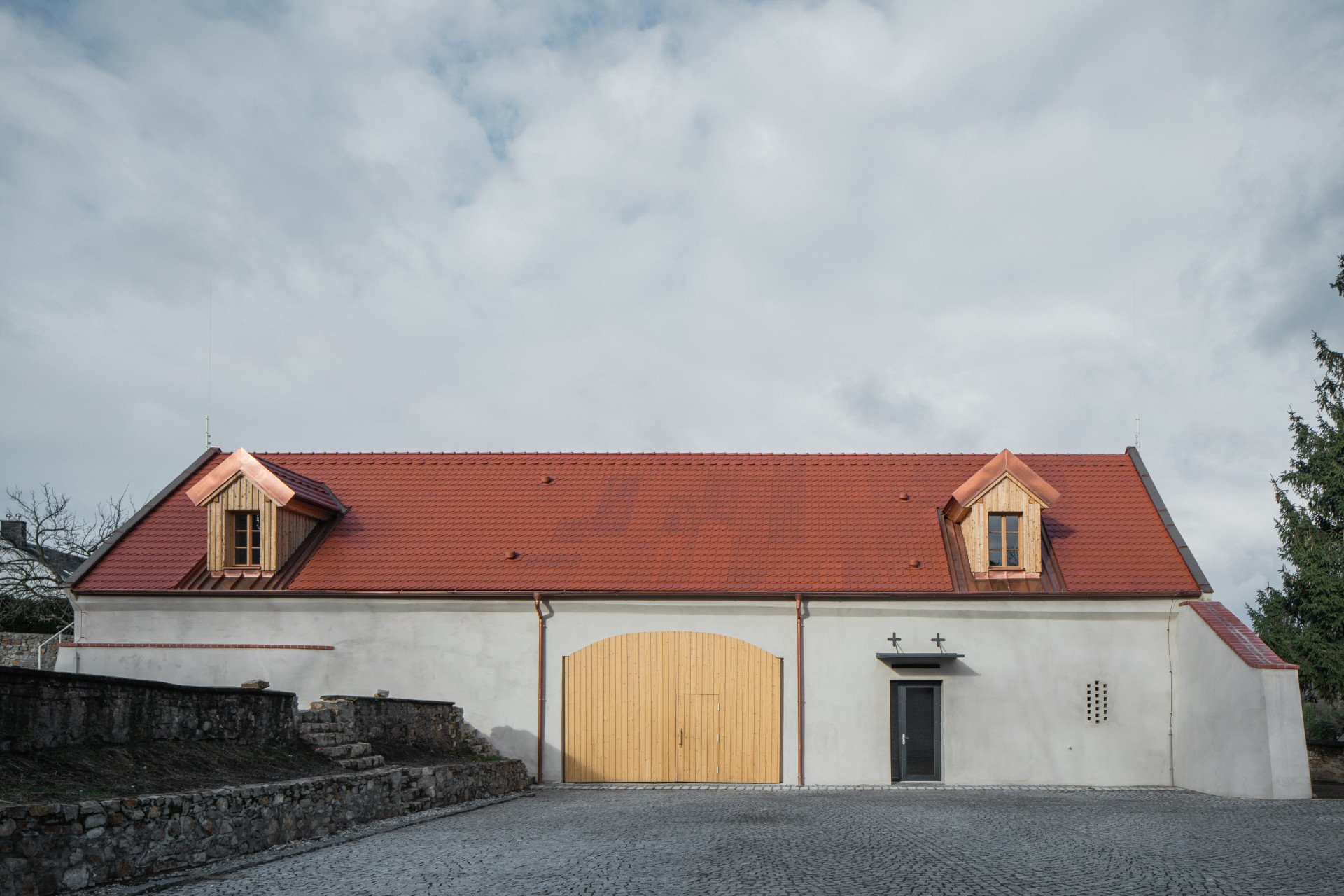Bývalá farní stodola se zavřenými vraty. (Komunitní centrum v bývalé stodole, studio Raketoplán)