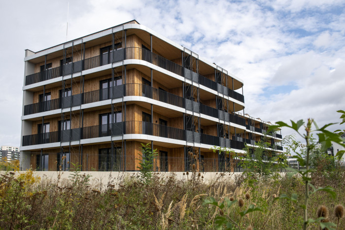 Čtyři bytovky, celkem 62 bytů. To je projekt Timber Praha developera UBM Development se sídlem v Rakousku. Právě z rakouské centrály přišel pokyn stavět ze dřeva, původně byly domy naplánovány jako železobetonové.