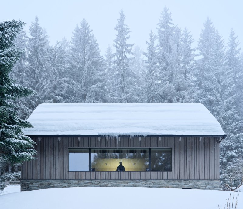 Stavba pracuje s pro lokalitu typickým kamenným soklem, fasádou obloženou modřínem a sedlovou střechou. (Chalupa Na Kukačkách; edit! architects)
