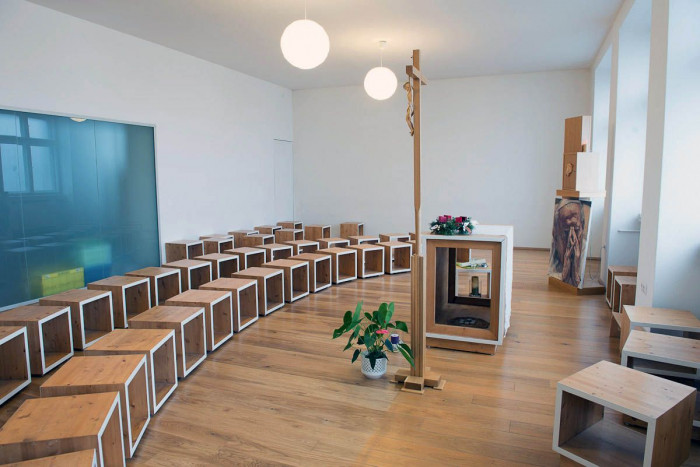 Dominantou priestoru je kríž a presklená stena, oddeľujúca svetský a duchovný priestor,