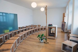 Dominantou priestoru je kríž a presklená stena, oddeľujúca svetský a duchovný priestor,
