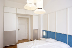 Ložnice je vybavena vestavěnými šatními skříněmi, které tvoří portál okolo vstupních dveří. (Byt na nábřeží, DDAANN)