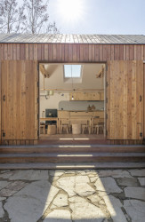 Děti do "obýváčku" chodí jíst, mohou v něm u velkého stolu kreslit anebo se schovat před příliš nepříznivým počasím. (Lesní třída Větvíci na Žižkově od ateliérů Terra Florida a Jasné)