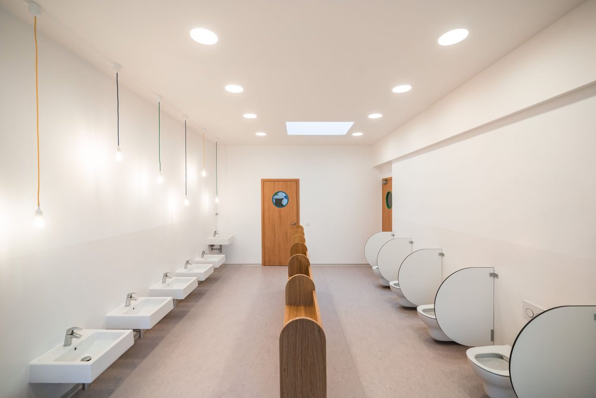 V koupelnách nejsou nemocniční dlaždičky, nýbrž stěrka a nátěr. (Mateřská škola ve Vědomicích, Architip)
