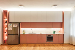 V bytě je výrazná kuchyně. Bílo-růžová linka navazuje na růžové závěsy a barevné akcenty v solitérním nábytku. (Byt na Novém Městě, Helena Ballošová)