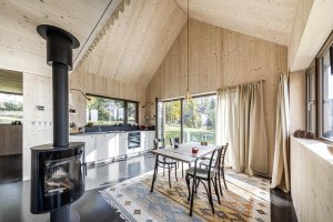 Hlavní místnost působí prostorně, a to hlavně proto, že se vertikálně otevírá do podkroví. (Chata v Kořenově, Facha architekti)