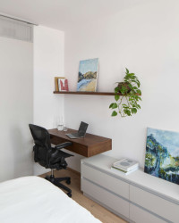 Ložnice sama o sobě pracuje s minimalistickým výrazem – doplňuje ji pracovní stůl a noční stolky z masivního dubu, které do interiéru vnášejí hřejivý akcent. (Interiér bytu Karlín; PANIKHORN)