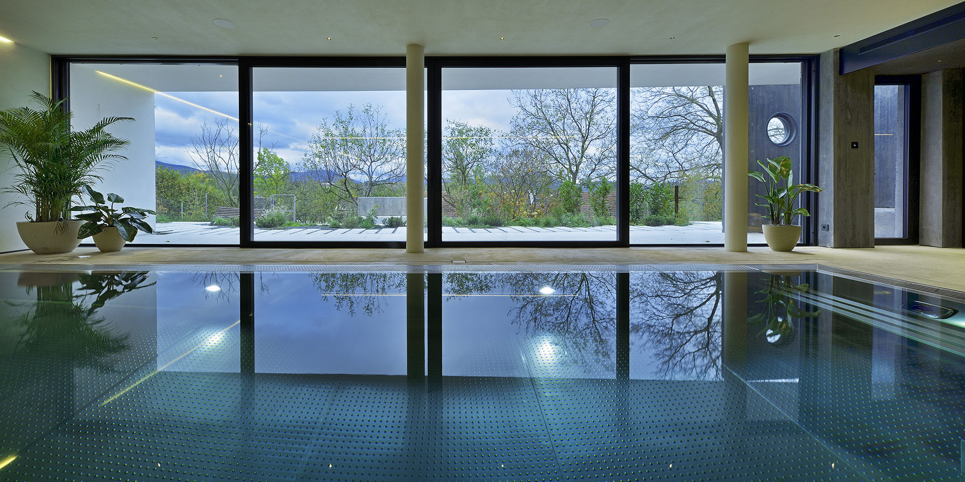 Nejnižší podlaží je z části zapuštěné pod terén, nachází se na něm bazén a posilovna.