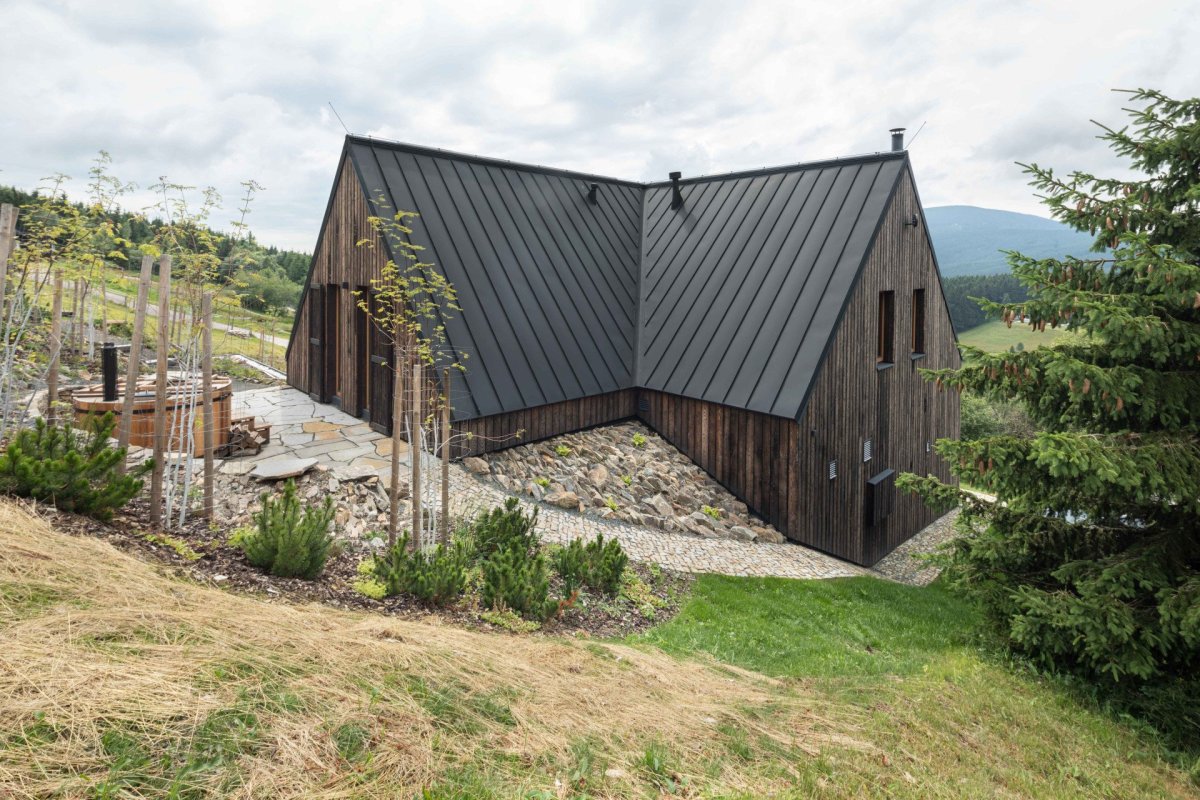 Chalupa sedí na vrstevnici v příkrém svahu. Vlastně se do něj „zakusuje“. (OK PLAN ARCHITECTS, Rodinná bouda)