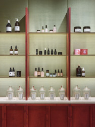 Showroom kosmetiky v Karlíně, P E T R I K + K O T R C & Nora Sopková: Horizontálně orientovaný regál má sokl a stojny jednotlivých polic namořeny do rudě červeného odstínu