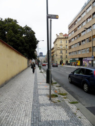 Praktičnost: Proč město povoluje umístění sloupků omezujících pohyb po chodníku v místě, kde vše důležité může být připevněno na stožáry veřejného osvětlení? Čtvrt chodníku jedné z nejrušnějších pražských ulic kvůli tomu nikdo nemůže používat ani uklízet, a tak mezi dlažbou roste tráva. / Žitná ulice v Praze – foto