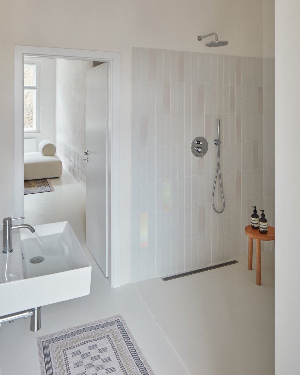Rekonstrukce bytu v Karlových Varech, Plus One Architects: V koupelně byl kreativně využit nepravidelný trojúhelníkový prostor, který nově obsadil velkorysý sprchový kout