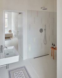 Rekonstrukce bytu v Karlových Varech, Plus One Architects: V koupelně byl kreativně využit nepravidelný trojúhelníkový prostor, který nově obsadil velkorysý sprchový kout