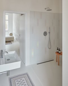 Rekonstrukce bytu v Karlových Varech, Plus One Architects: V koupelně byl kreativně využit nepravidelný trojúhelníkový prostor, který nově obsadil velkorysý sprchový kout