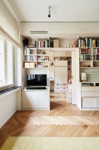 Příčka mezi obytným prostorem a ložnicemi již byla. Architekta do ní pouze navrhla více otvorů, pouzdra posuvných dveři a schovala ji za knihovnu. (Rekonstrukce bytu na Vinohradech, Markéta Bromová architekti)