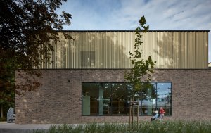 Aquavparku v Kyjově, SENAA architekti: Bazénová hala je proto hmotově rozdrobená. Parter je pevný, tvoří ho táhlá stěna obložená cihelnými pásky.