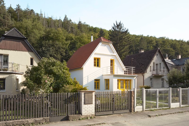 Světle omítnutá stavba se  i po rekonstrukci výrazně podobá svým sousedům. (Rekonstrukce prvorepublikového domu v údolí, 0,5 Studio)