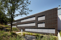 Fasáda budovy je kryta laťovým roštem, který jí dává přírodní charakter - foto