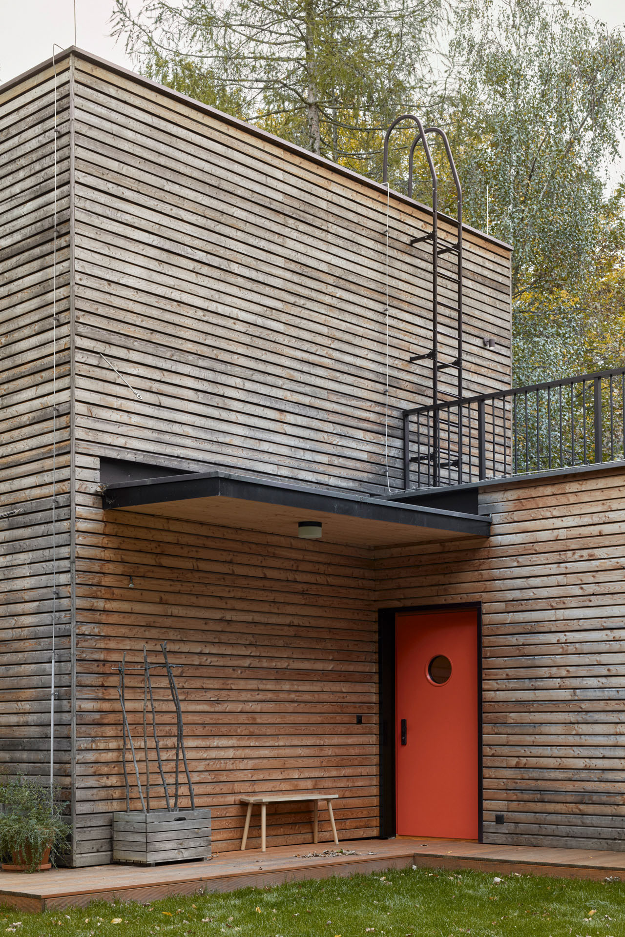 Jemné odkazy na funkcionalismus – červené dveře s kulatými okénky připomínajícími lodní kajutu nebo žebřík vedoucí na střechu. (Dům v Davli, 0,5 Studio)