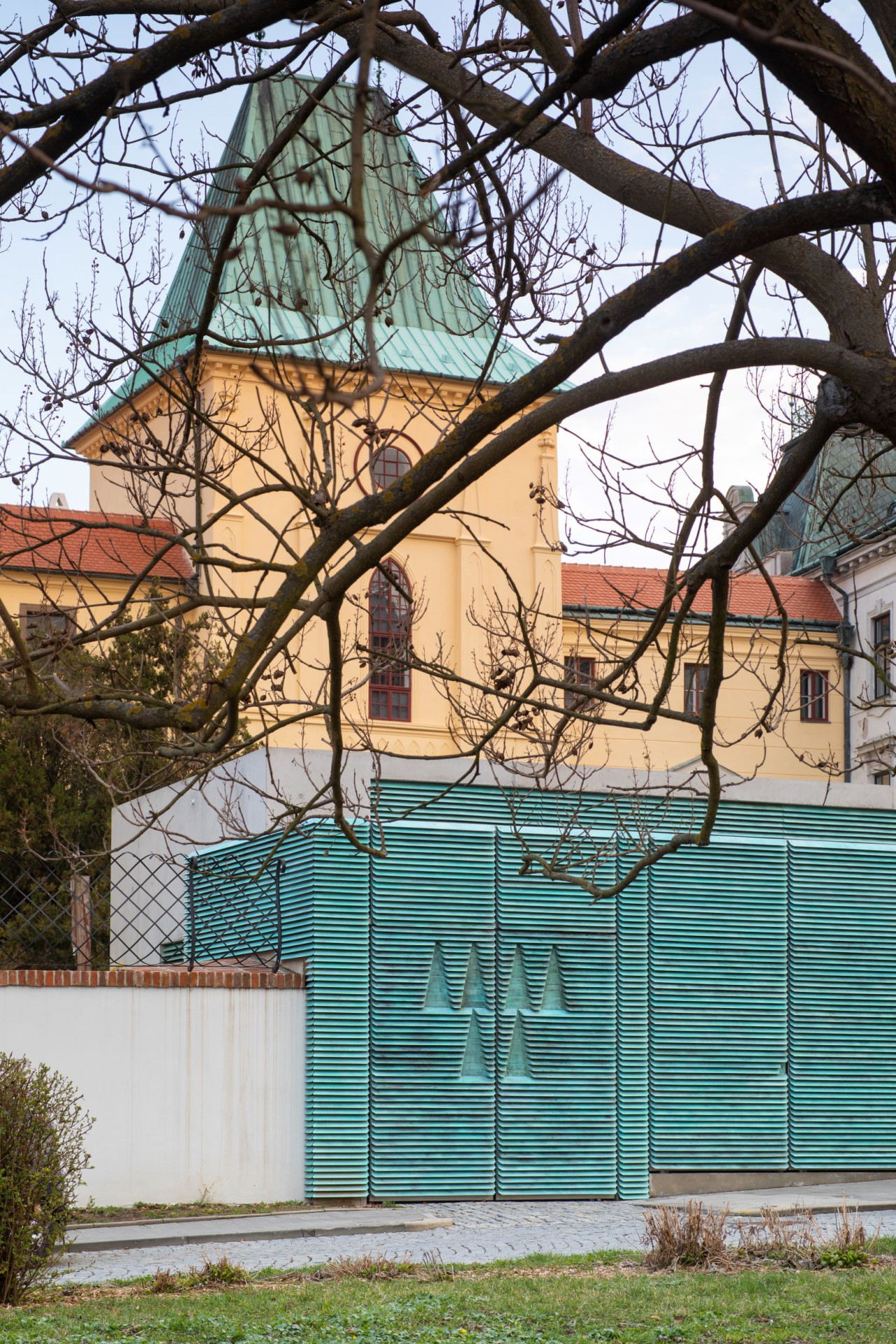 Znak Arcibiskupství olomouckého - prolisovaný na vratech brány, za kterými je vchod do zámeckých sklepů. (Vstupní objekt do zámeckých sklepů s trafostanicí v Kroměříži od Atelier Štěpán)