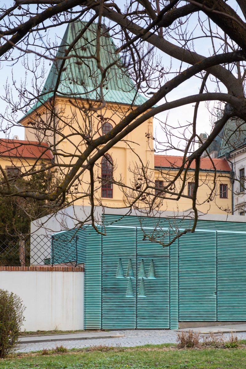 Znak Arcibiskupství olomouckého - prolisovaný na vratech brány, za kterými je vchod do zámeckých sklepů. (Vstupní objekt do zámeckých sklepů s trafostanicí v Kroměříži od Atelier Štěpán)