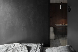 Ložnici od kuchyně s obývacím pokojem odděluje příčka s částí z perforovaného kovu. (Apartmán v Jizerských horách, MAVA ARCHI)