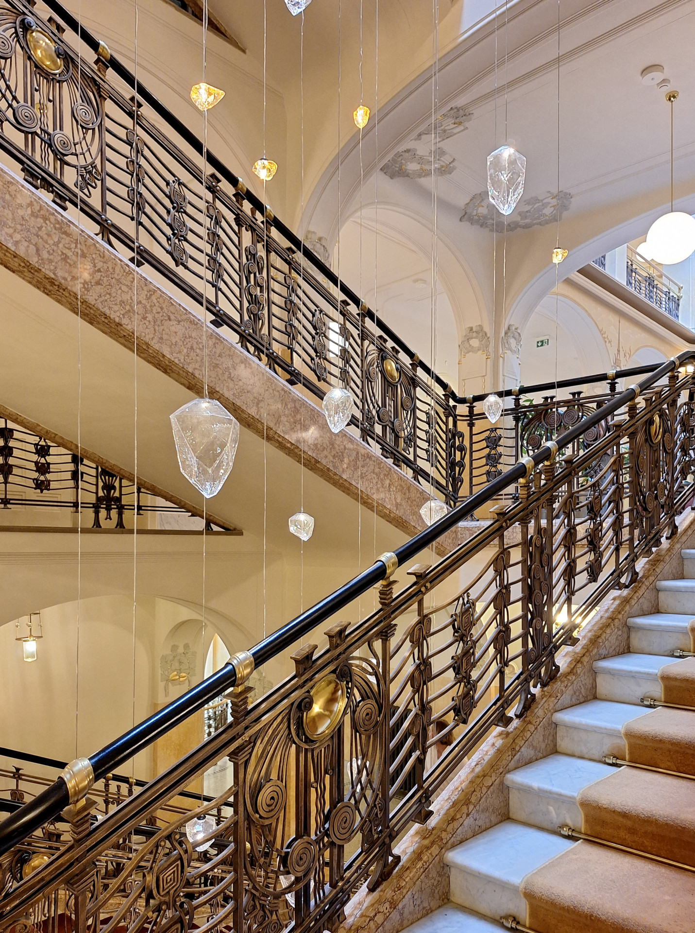 Řadu svítidel do secesních i nových interiérů vyrobila Preciosa. Mezi rameny původního schodiště visí skleněné krystaly.