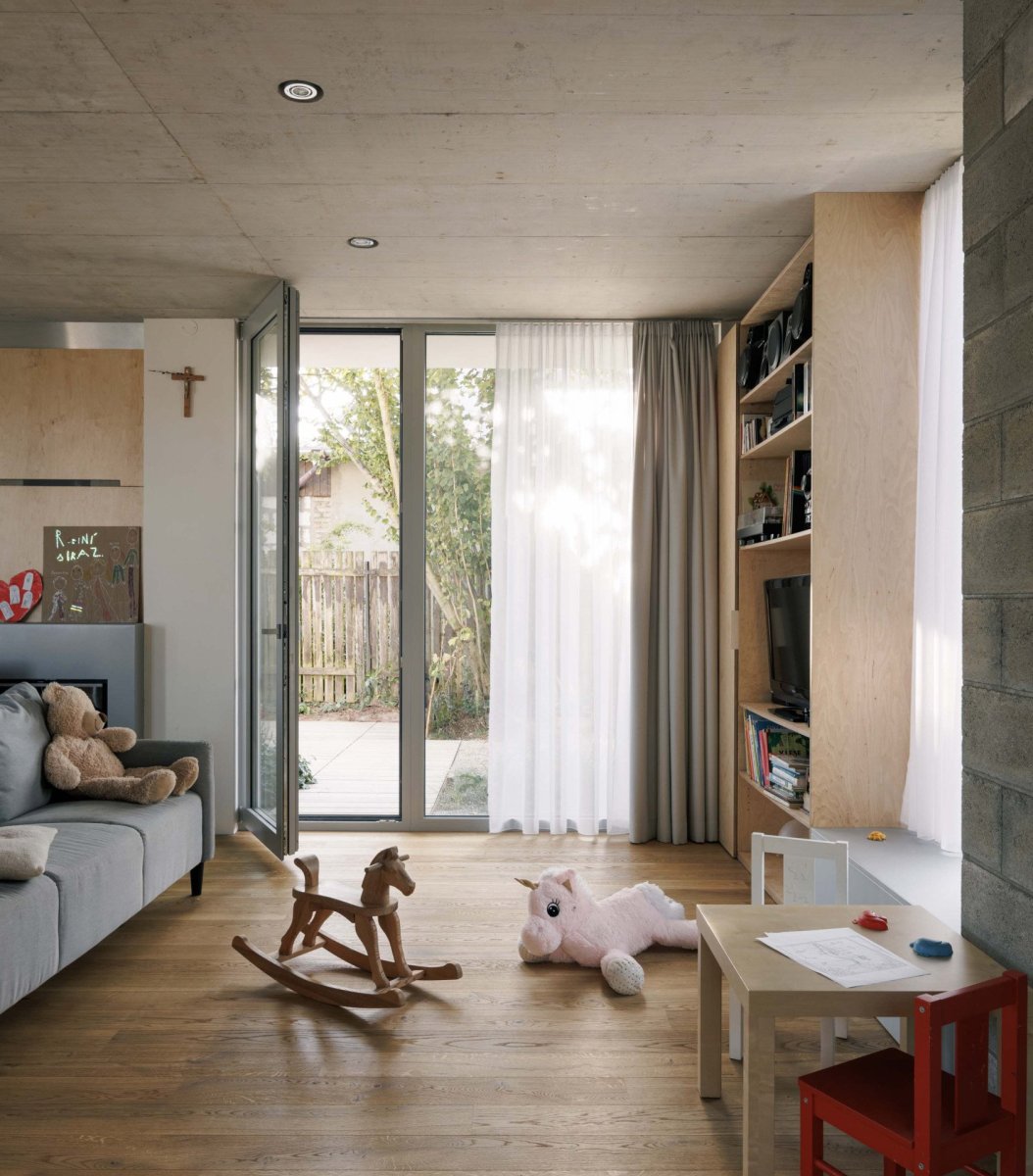 Do hlavního obytného prostoru ústí kuchyň, knihovna, krb a oddělitelné schodiště. (Rodinný dům v Radotíně, Papundekl architekti)