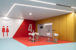 Přírodní podlaha Marmoleum Fresco v kombinaci odstínů modré 3267 a červené 3131. Právě červený odstín byl instalován na stěnu jako součást navigačního systému.