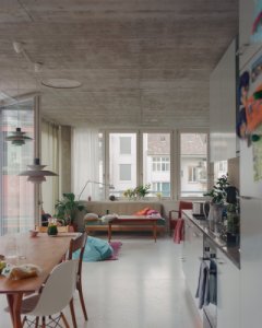 Obývací pokoj s kuchyní má celou prosklenou stěnu s výstupem na balkon. (Komunitní bydlení v bývalé industriální zóně; Clauss Kahl Merz Atelier)