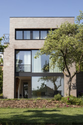 Fasádu s tmavým cihelným obkladem na ní rozbíjejí velkoformátová okna