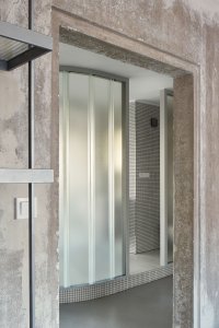 Byt sochaře, NEUHĀUSL HUNAL: Vysoké skleněné profily vytvářejí transparentní příčky, které matně rozmazávají dění na druhé straně, ale plně nechávají prostoupit světlo všemi kouty půdorysu