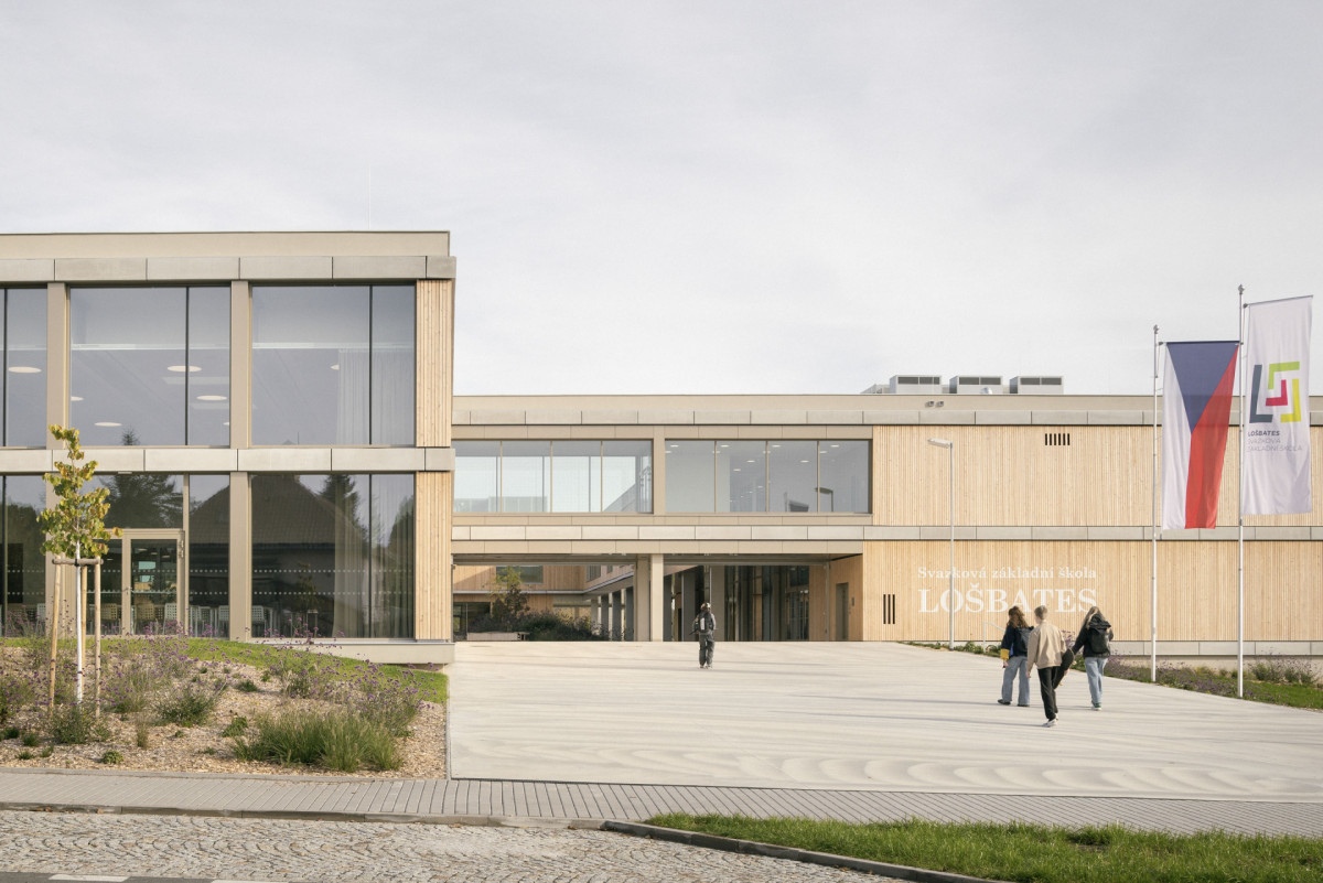 Základní školu navrhl ateliér SOA architekti a složil ji ze čtyř provázaných hmot, které dohromady uzavírají čtvercový dvůr. Uprostřed něj je hřiště, kde se děti mohou bezpečně scházet, hrát si i trávit čas mezi výukou.

