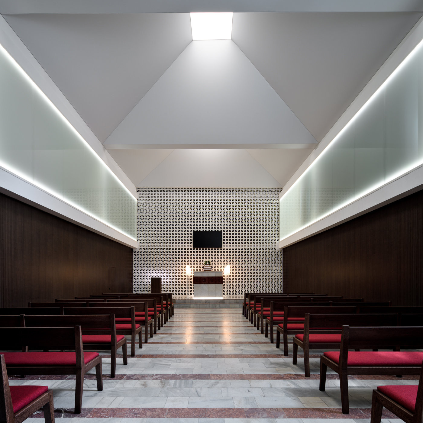 Namořené dřevo v kontrastu s bílou barvou a světlem vedeným z krovu vytváří harmonickou atmosféru (Interiér smuteční síně; Atelier 38)