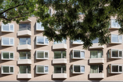 Jak do místa vstupuje? Především proskleným parterem a pak také svou expresivní fasádou s vystupujícími hliníkovými okny a balkony a kabřincovým keramickým obkladem. Zajímavá je technologie výstavby, dům je z prefabrikovaných betonových panelů.