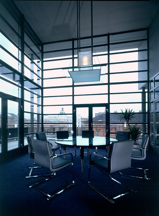 Stavba, realizovaná na základě vítězství v architektonické soutěži, se stala jednou z prvních velkých porevolučních realizací v centru Brna. Architekti Aleš Burian a Gustav Křivinka se na nároží Joštovy a České ulice rozhodli navázat na slavnou tradici brněnské meziválečné architektury. Budově s vysokým parterem tak dali jednoduchou fasádou s bílým kamenným obkladem a širokými okny vysunutými až do líce fasády.