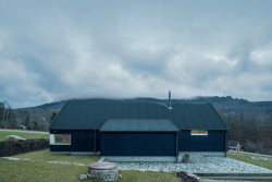 Chata v Jizerských horách, Markéta Cajthamlová, Architektonická projekční kancelář: Sokl domu je ze světlého pohledového betonu, fasáda pak z vertikálně kladeného prkenného obkladu v tmavě modré barvě