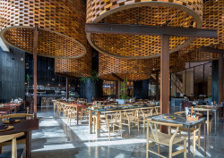 Pro větší skupinu lidí je k dispozici stůl se skleněnou deskou, ke kterému se vejde až 12 osob. (Restaurace Pizza 4P’s v Hanoji od česko – vietnamského studia ODDO)