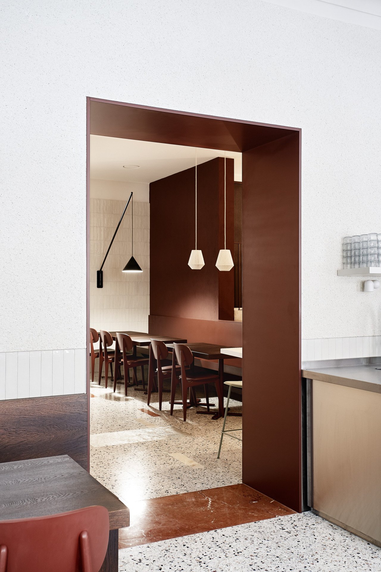Hnědočervená barví také průchod do zadní místnosti kavárny. (Mezi Srnky, Markéta Bromová Architekti)