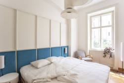 Za postelí je velké čelo seskládané z panelů čalouněných azurovým sametem. (Byt na nábřeží, DDAANN)