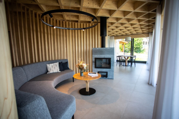 Obývací pokoj je od zbytku prostoru oddělen dřevěným půlkruhem, jenž vytváří intimní, až kavárenskou atmosféru.(Vila Sobeš v Sedlešovicích, arch. návrh: Noa architekti, generální dodavatel stavby: VESPER HOMES) 