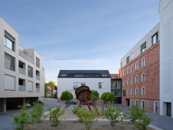 Naproti historickým objektům vznikly nové bytové domy. Mezi nimi náměstí s turbínou. (mar.s architects, obnova Žitného mlýna v Boršově nad Vltavou)